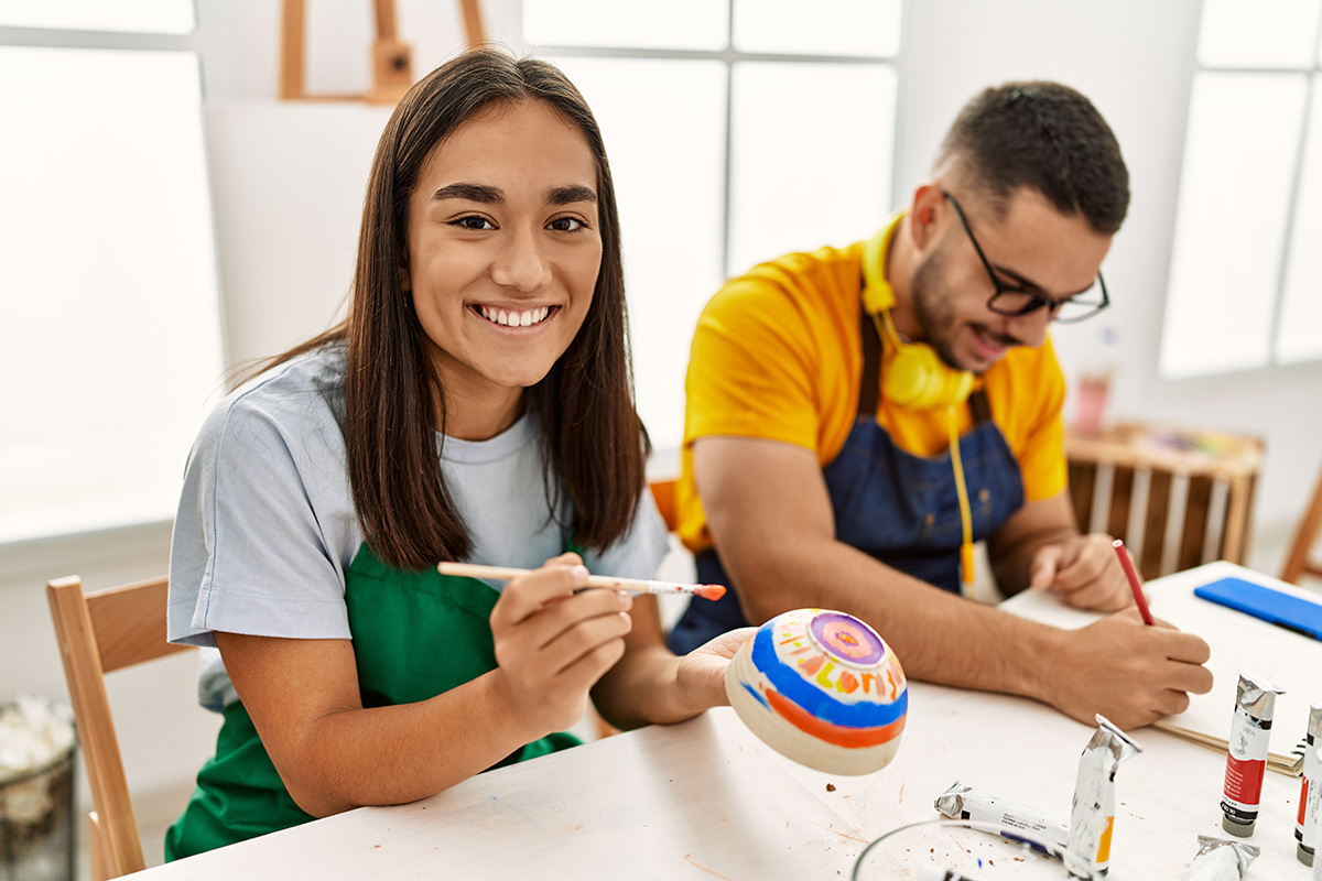 Young hispanic couple smiling happy drawing sitting on the table at art studio. workshop series