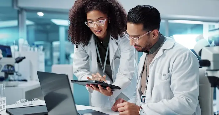 Two medical researchers in lab coats collaborating in a high-tech laboratory, representing career opportunities for adults with autism in healthcare, science, and engineering support roles.