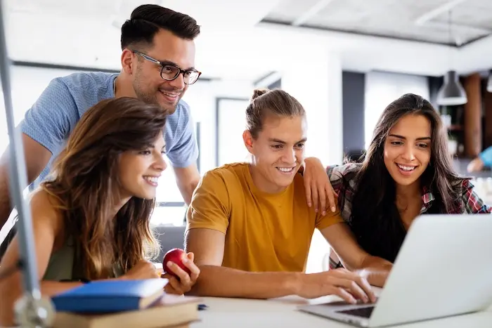 A diverse group of professionals collaborating in a bright office, with a woman leading a discussion over a laptop, highlighting inclusive workplace culture and career opportunities for autistic adults.