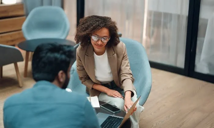 Young Black woman helping a young Indian man select a job training program.