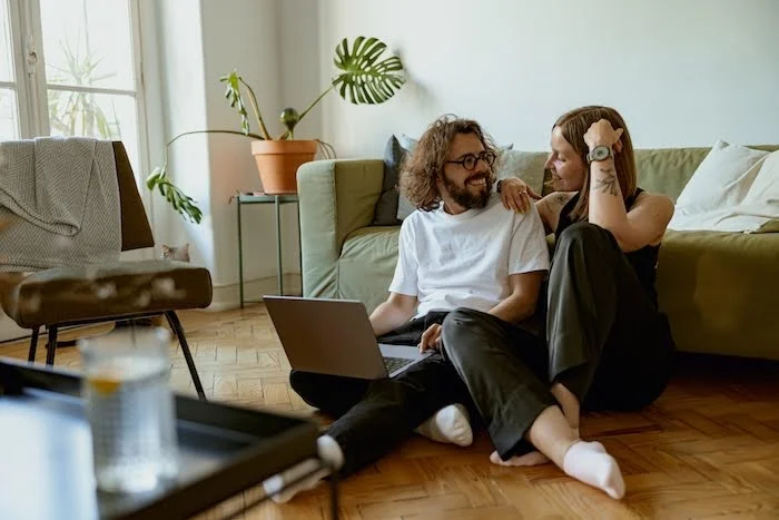 Young Caucasian couple smiling with their open laptop at home.