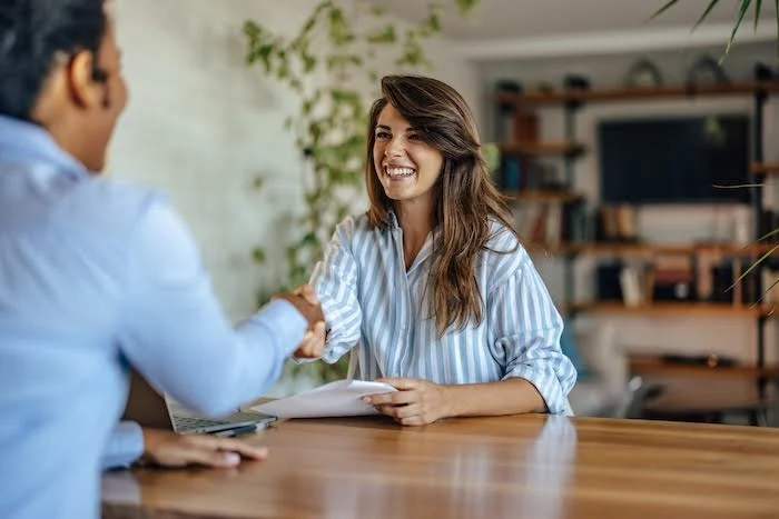 Young Indian man shaking hands with a young Caucasian woman after a job interview.