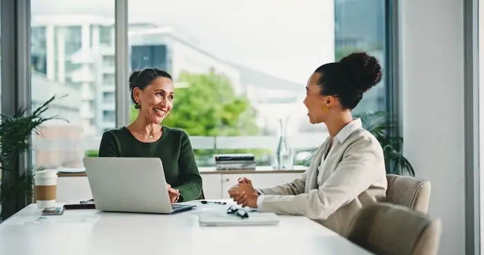 A smiling professional woman engaging in a job interview or career counseling session with a candidate, illustrating the supportive environment of autism employment services in California.