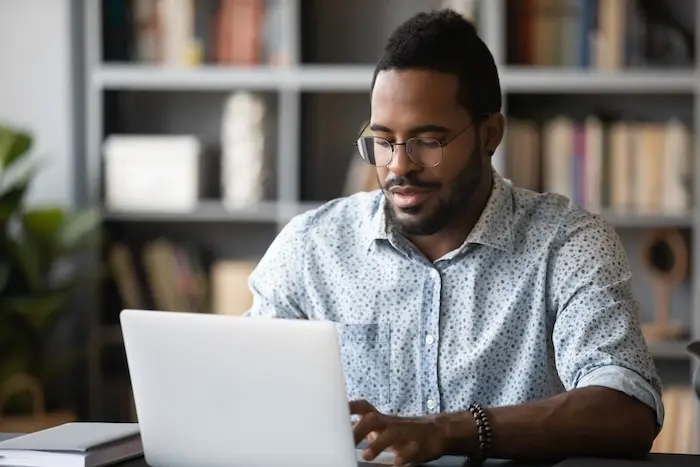 An adult with autism focusing intently while working on a laptop in a bright, modern office setting, representing neurodiversity and successful employment in California.